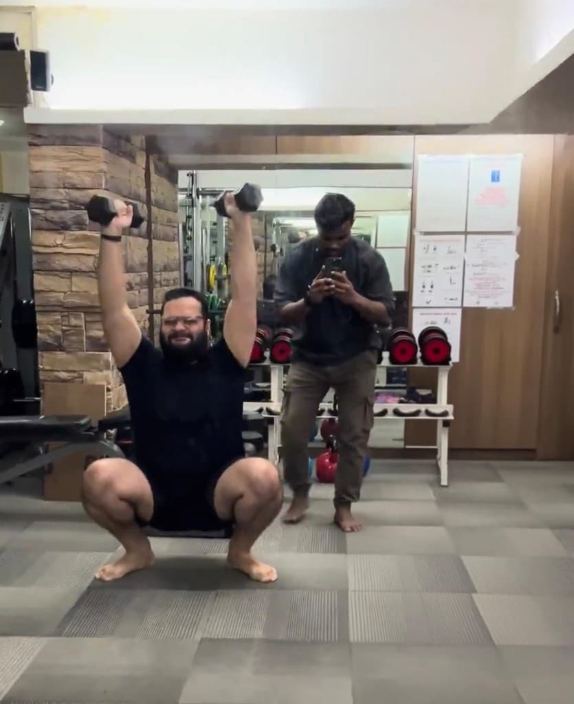 Same client performing a deep overhead squat with dumbbells after coaching progress